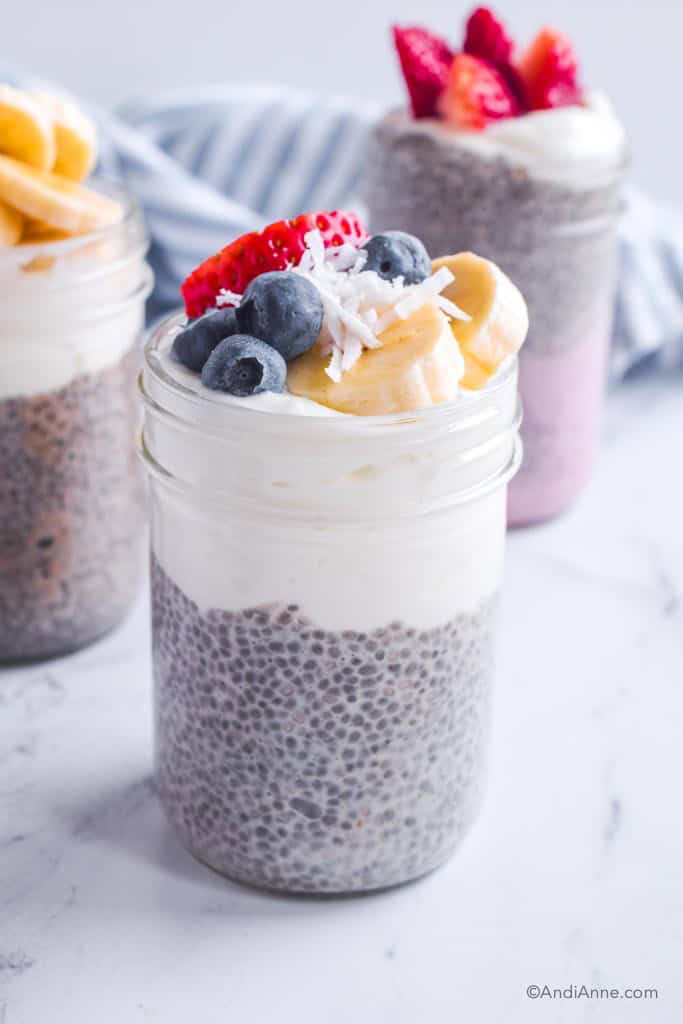 Vanilla chia pudding in mason jar topped with greek yogurt, blueberries, sliced banana, strawberry, and shredded coconut.