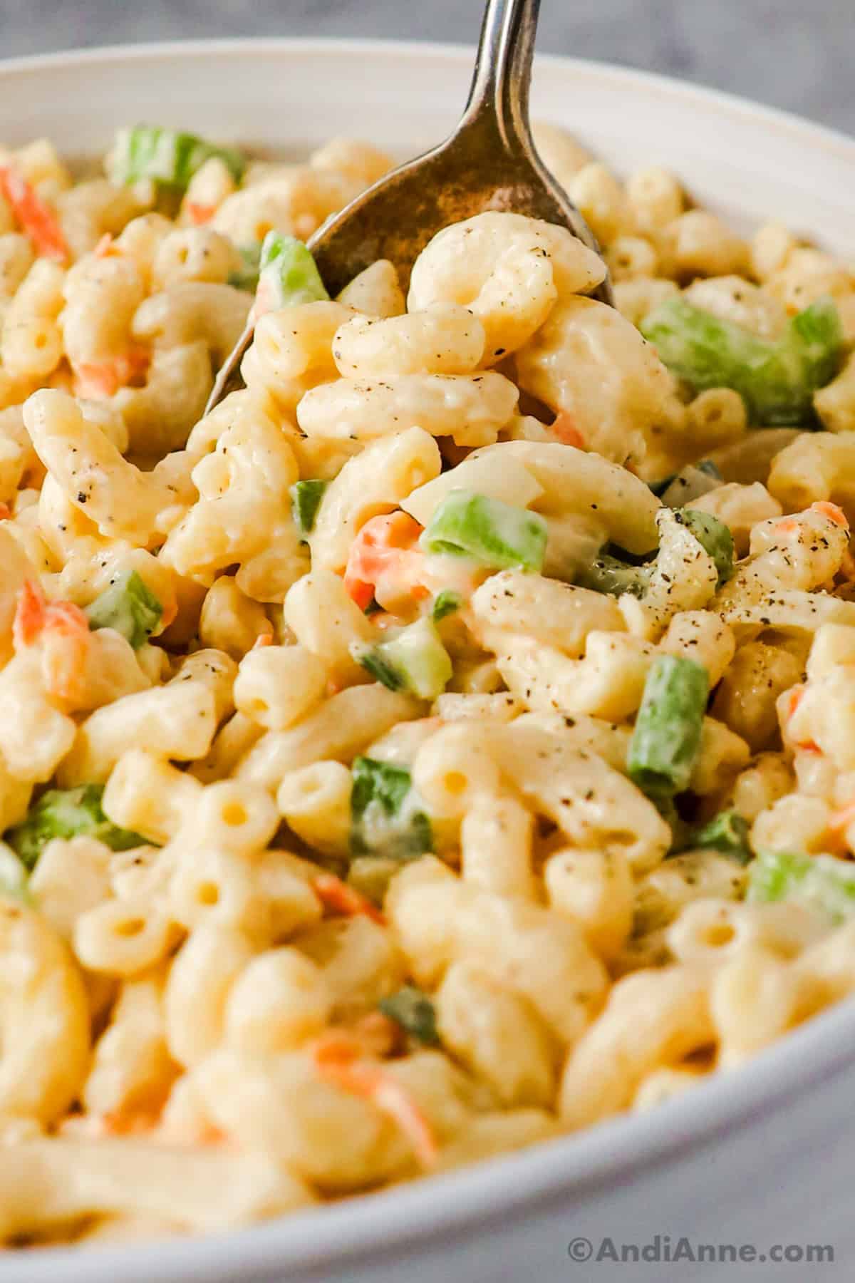close up of hawaiian macaroni salad with pasta, carrots and green onion in a creamy dressing.