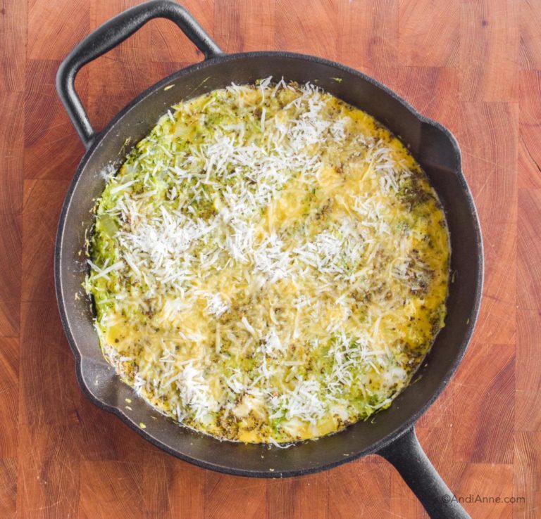 parmesan sprinkled on top of zucchini frittata in cast iron skillet