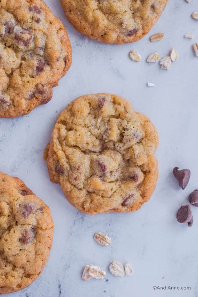 four chocolate chip oat cookies with a sprinkle of rolled oats and a few chocolate chips on counter