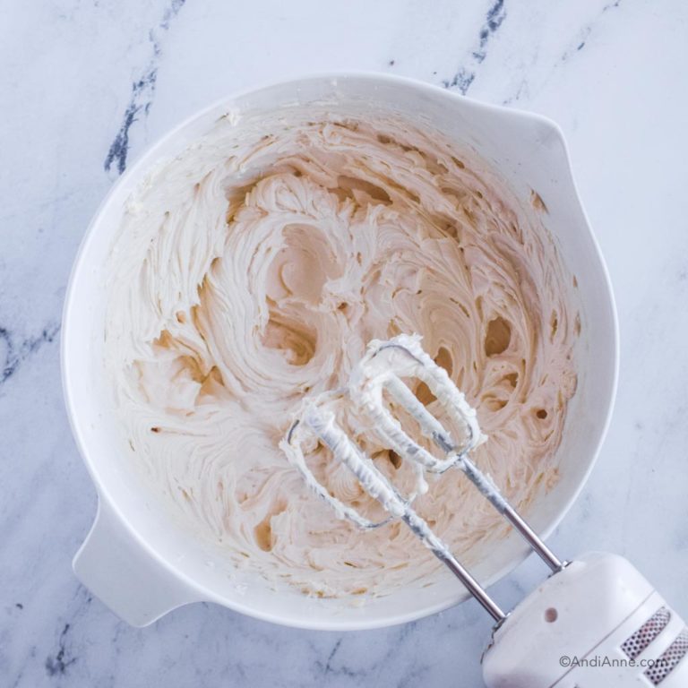 beaten cream cheese mixture in white bowl with hand mixer beside it