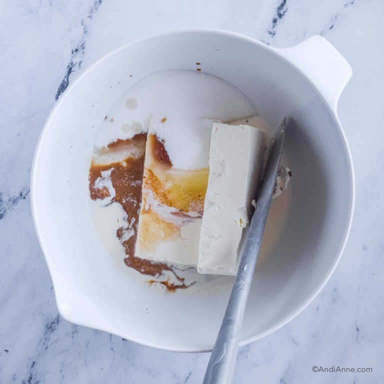 white bowl with cream cheese, vanilla and heavy cream and spatula