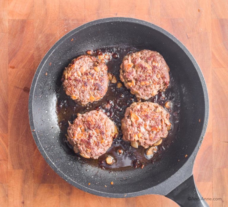 four cooked mushroom beef patties in a frying pan