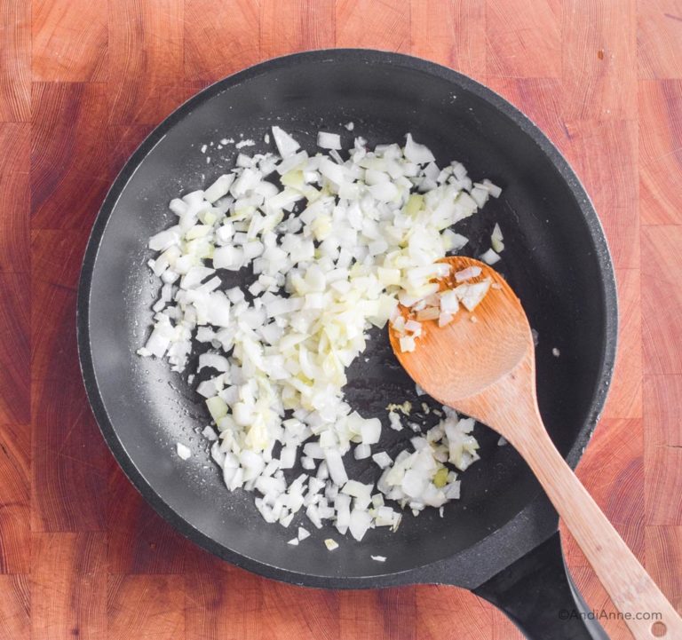 chopped onion in a frying pan with wood spatula