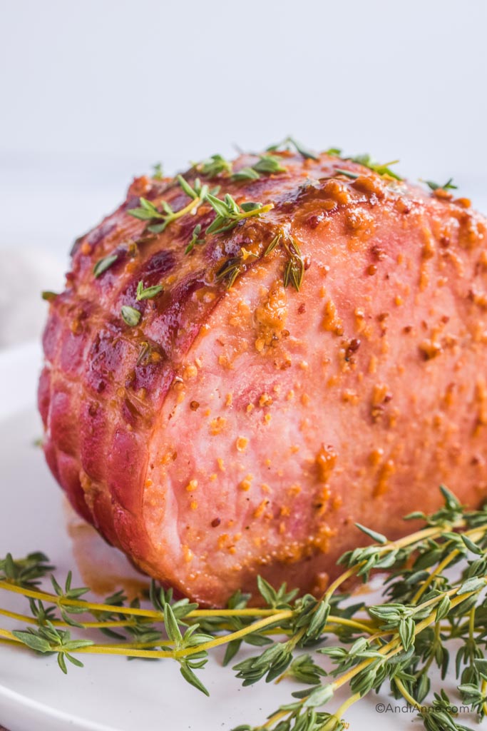 Honey mustard thyme glazed ham with fresh thyme placed in front. 