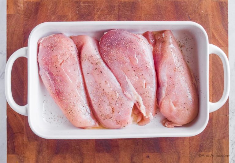 raw chicken breasts in white baking dish seasoned with salt and pepper