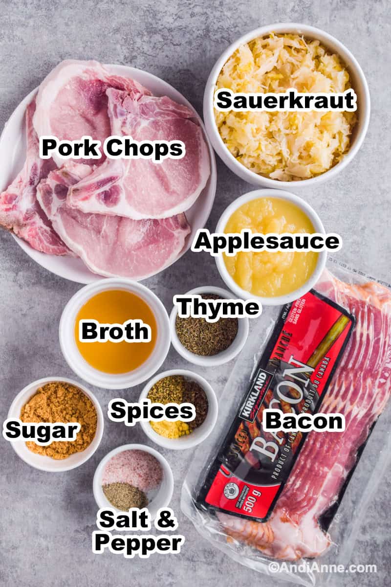 Ingredients to make recipe including plate of raw pork chops, bowl of sauerkraut, pack of bacon, bowl of applesauce, and bowls of spices.