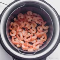 Looking down at air fryer with shrimp inside.