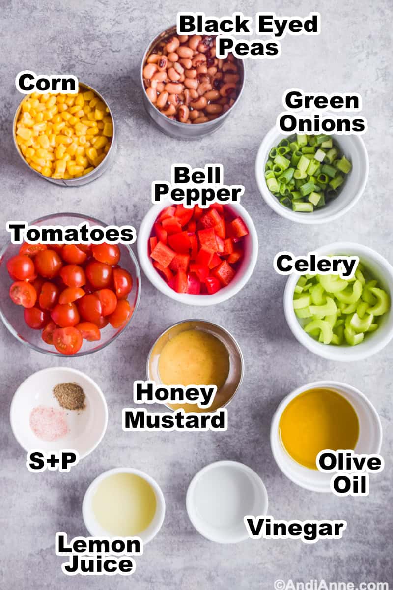 Ingredients to make recipe on counter including can of black eyed peas, bowl of tomatoes, bell pepper, green onions, honey mustard, olive oil and vinegar.