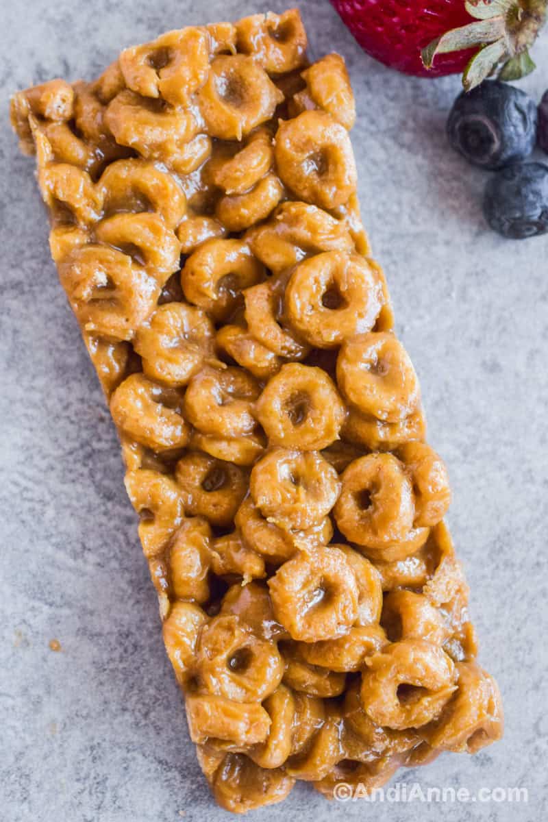 One homemade rectangular Cheerio bar with berries beside it.