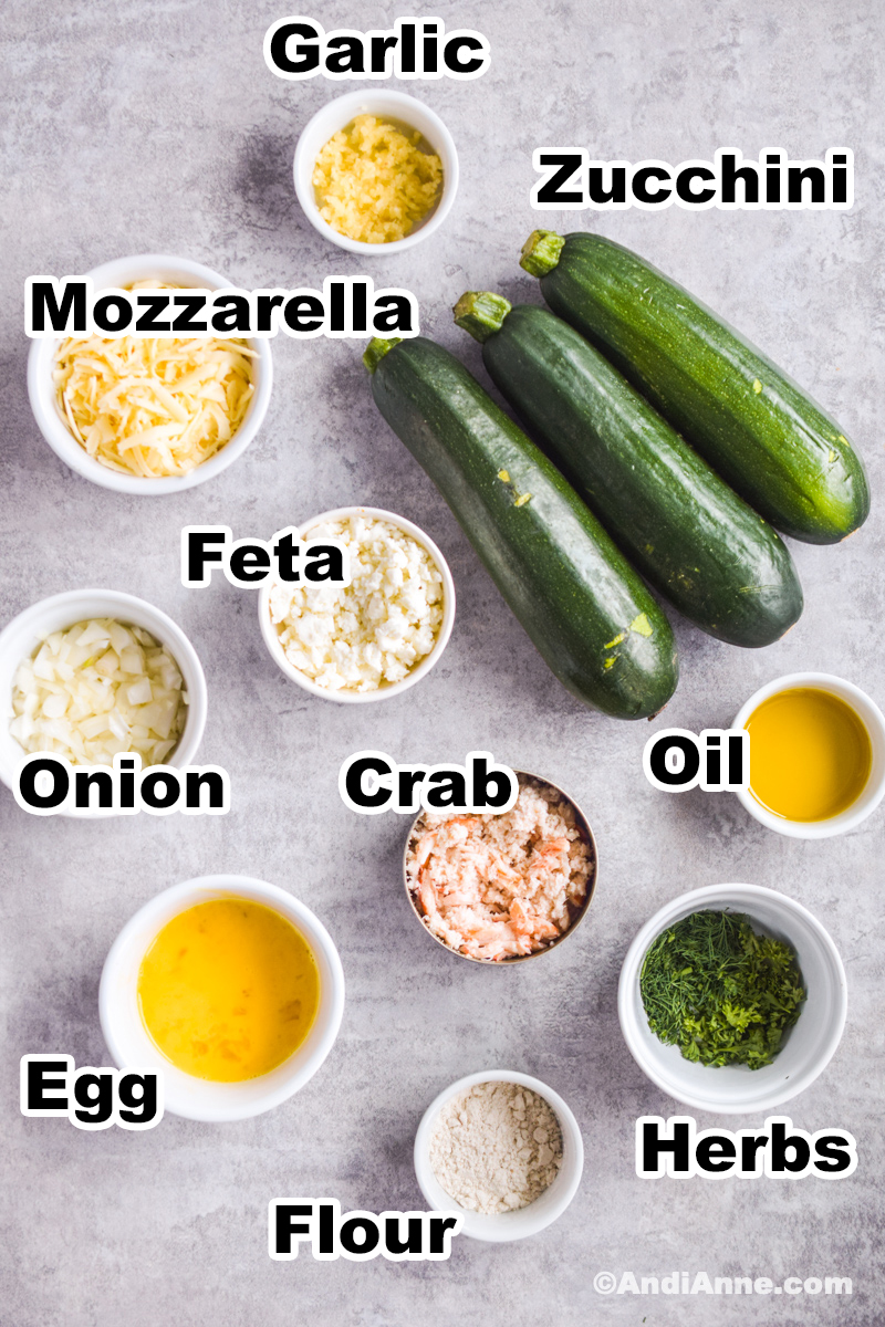 Ingredients to make the recipe including bowls of mozzarella, feta, onion, egg, crab, flour and three fresh zucchinis.