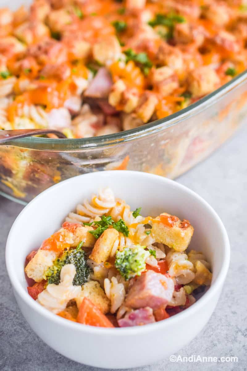 Small bowl with casserole ingredients and casserole dish blurred in background.