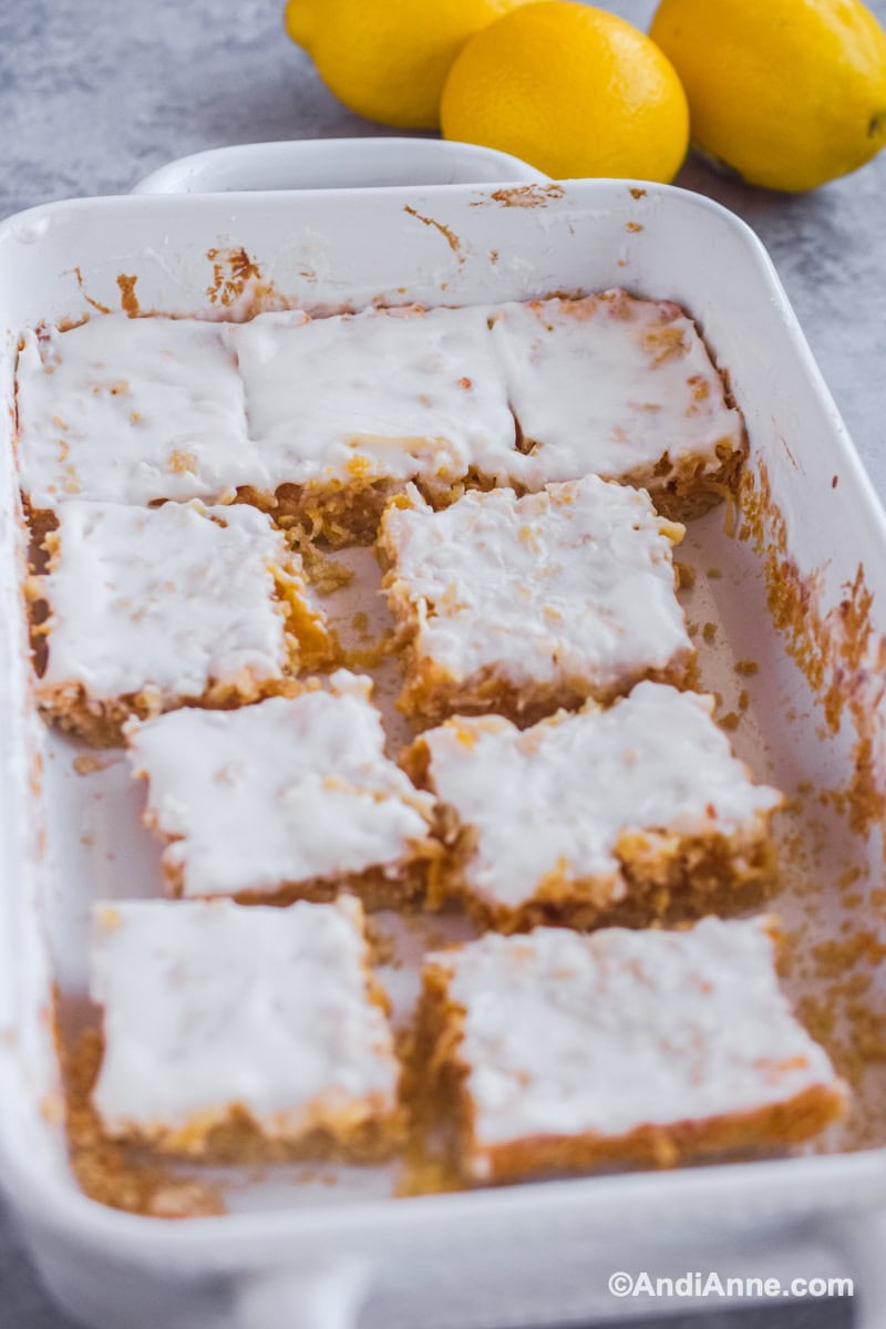 White baking dish with a few lemon coconut squares cut out and inside.
