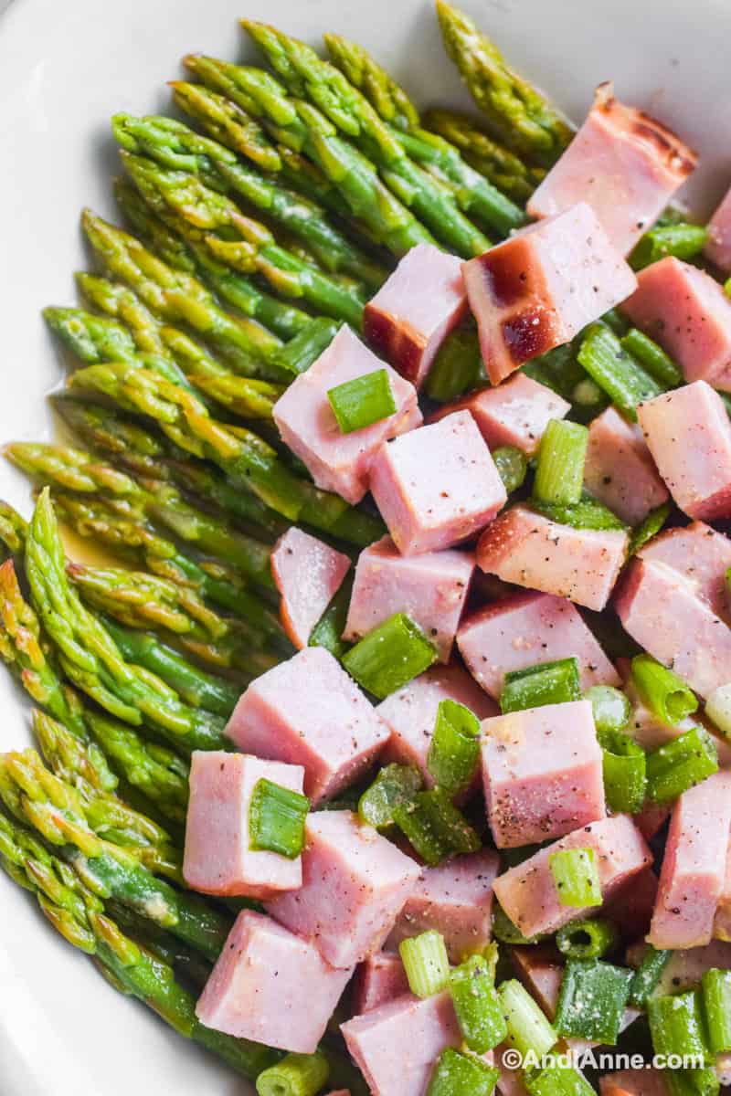 Close up of asparagus, chopped ham and green onion salad.