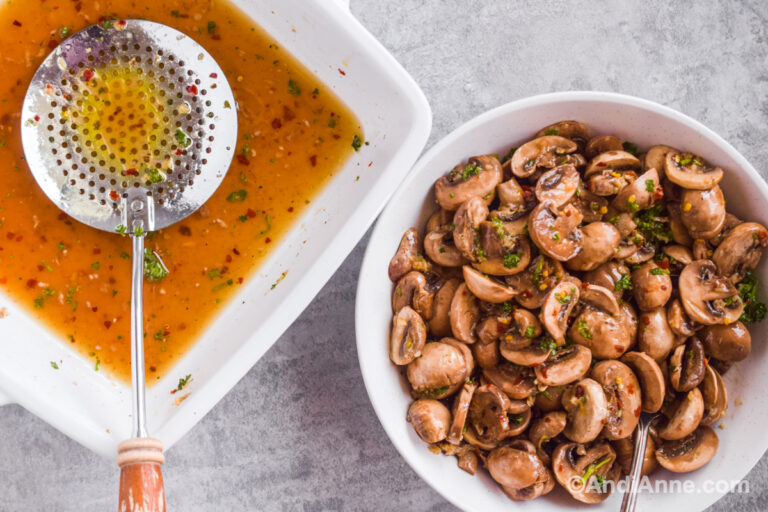 Square dish with leftover marinade, slotted spoon and bowl with marinated mushrooms beside it.
