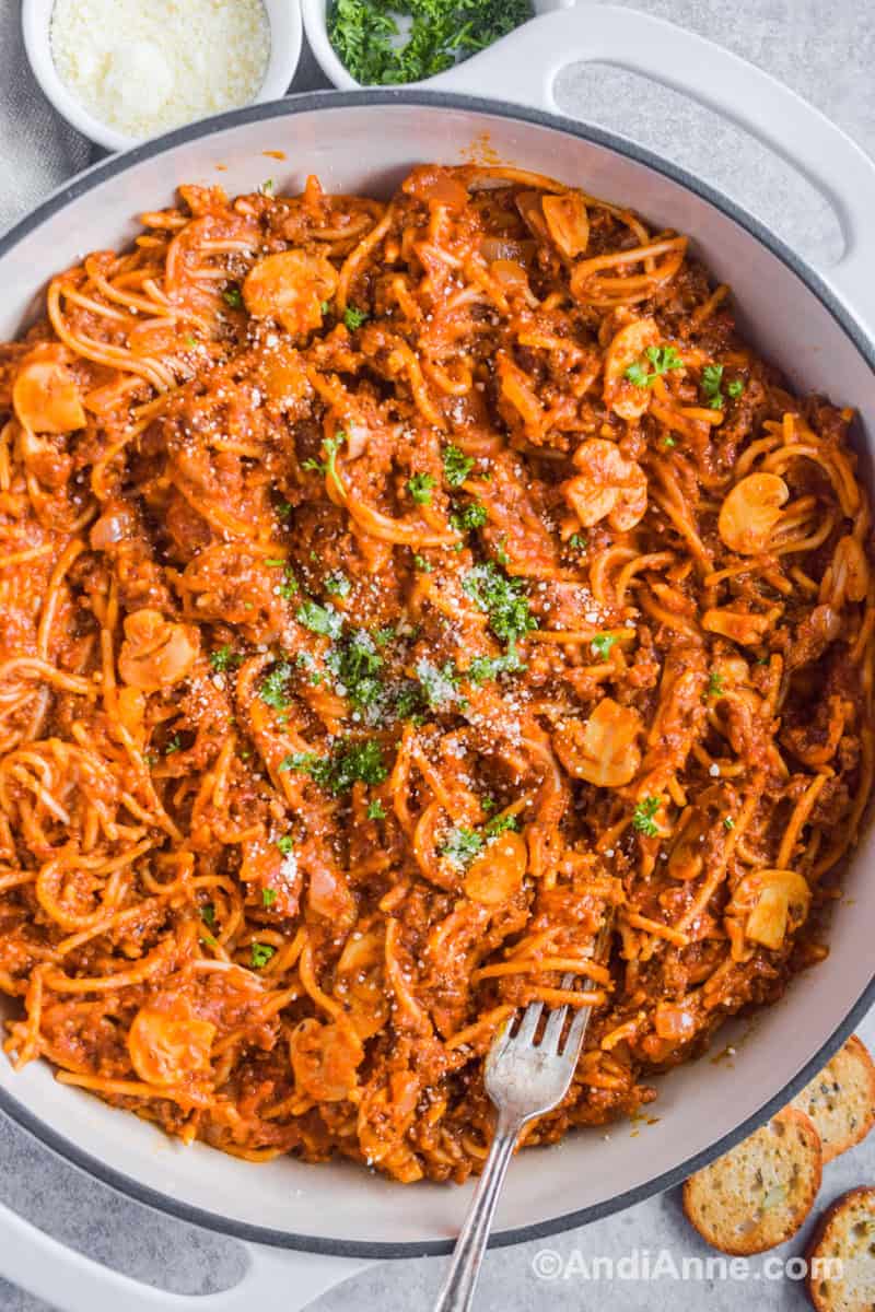 Close up of spaghetti in a white pot with a fork.