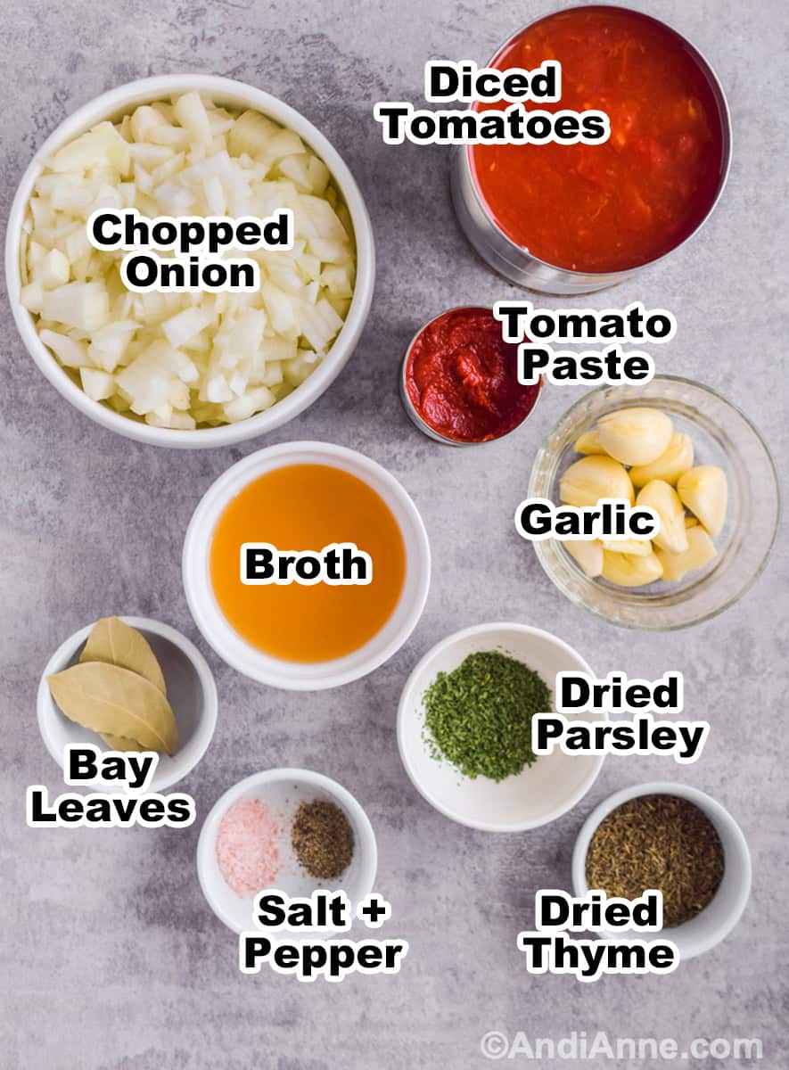 Ingredients to make recipe including bowl of chopped onion, can of diced tomato, bowl of garlic cloves, small bowls of herbs, and bowl with broth.