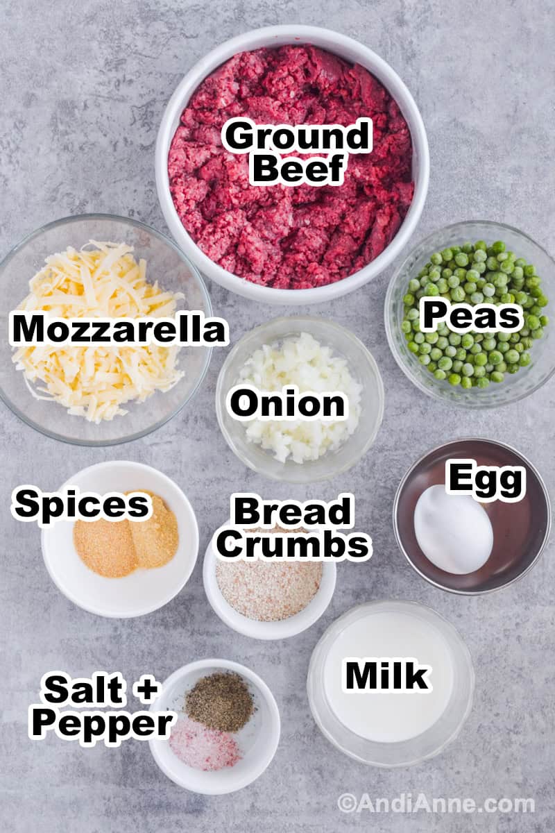 Ingredients for recipe on the counter including bowl of ground beef, bowl of frozen peas, shredded mozzarella, spices, bread crumbs and milk.