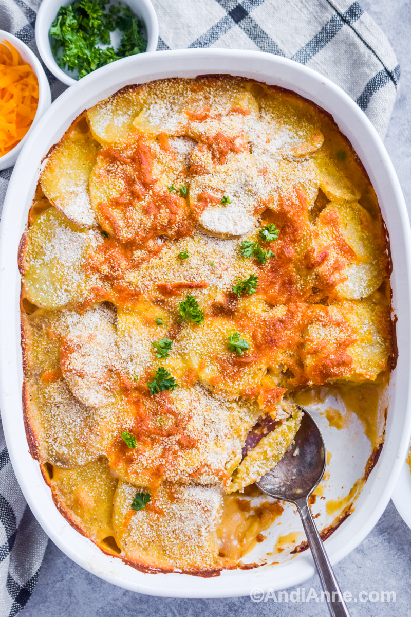 Potatoes au gratin with breadcrumbs in a white casserole dish with a serving taken out of the corner.