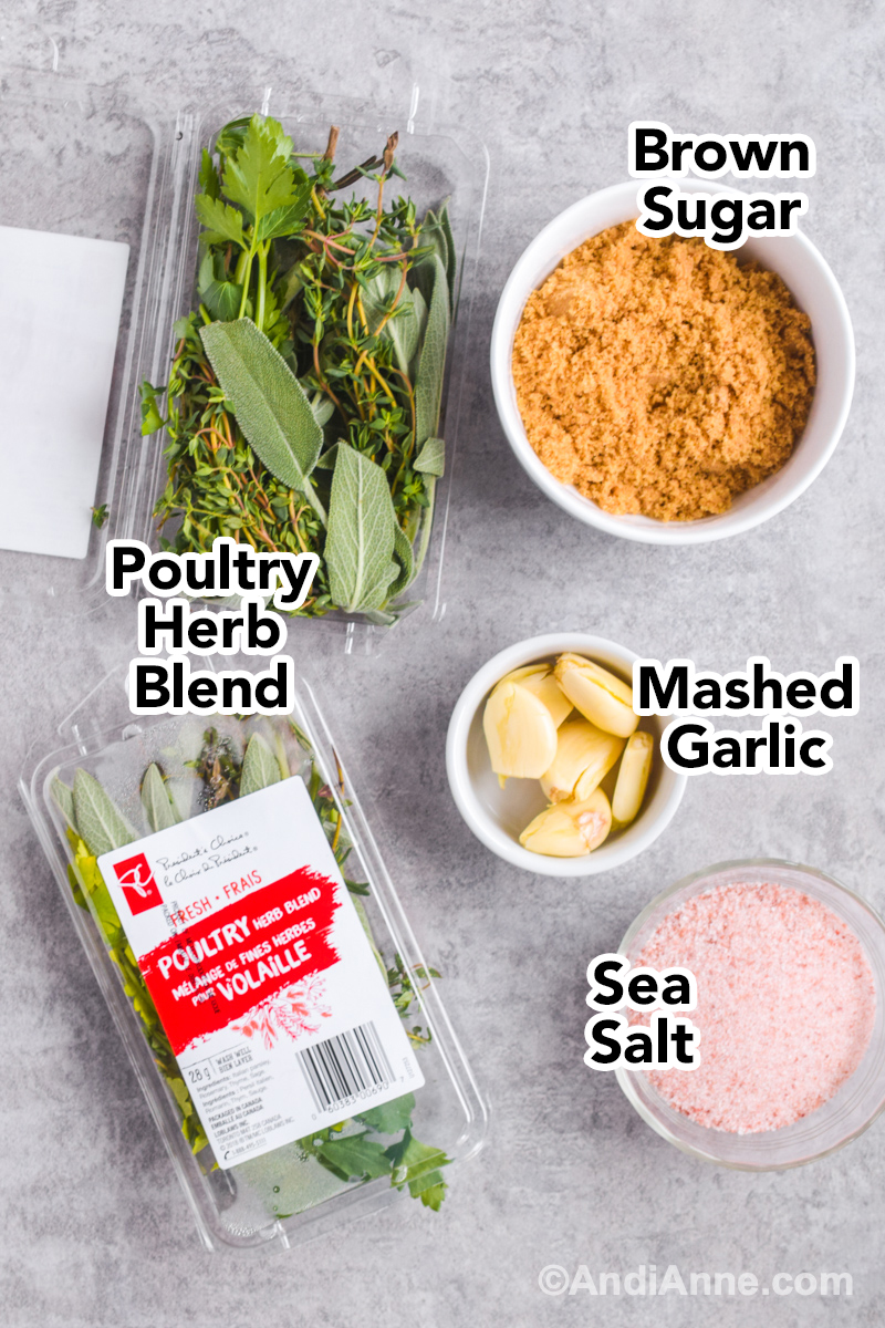 Recipe ingredients on a table including two packages of poultry herb blend, cup of brown sugar, garlic cloves and sea salt.