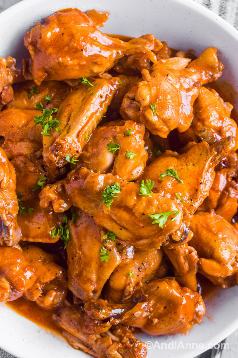 Close up of saucy barbecue chicken wings with a sprinkle or fresh parsley on top. 