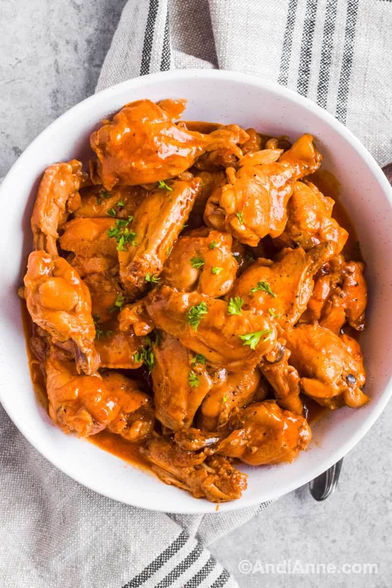 A white bowl with saucy barbecue ranch chicken wings piled inside.