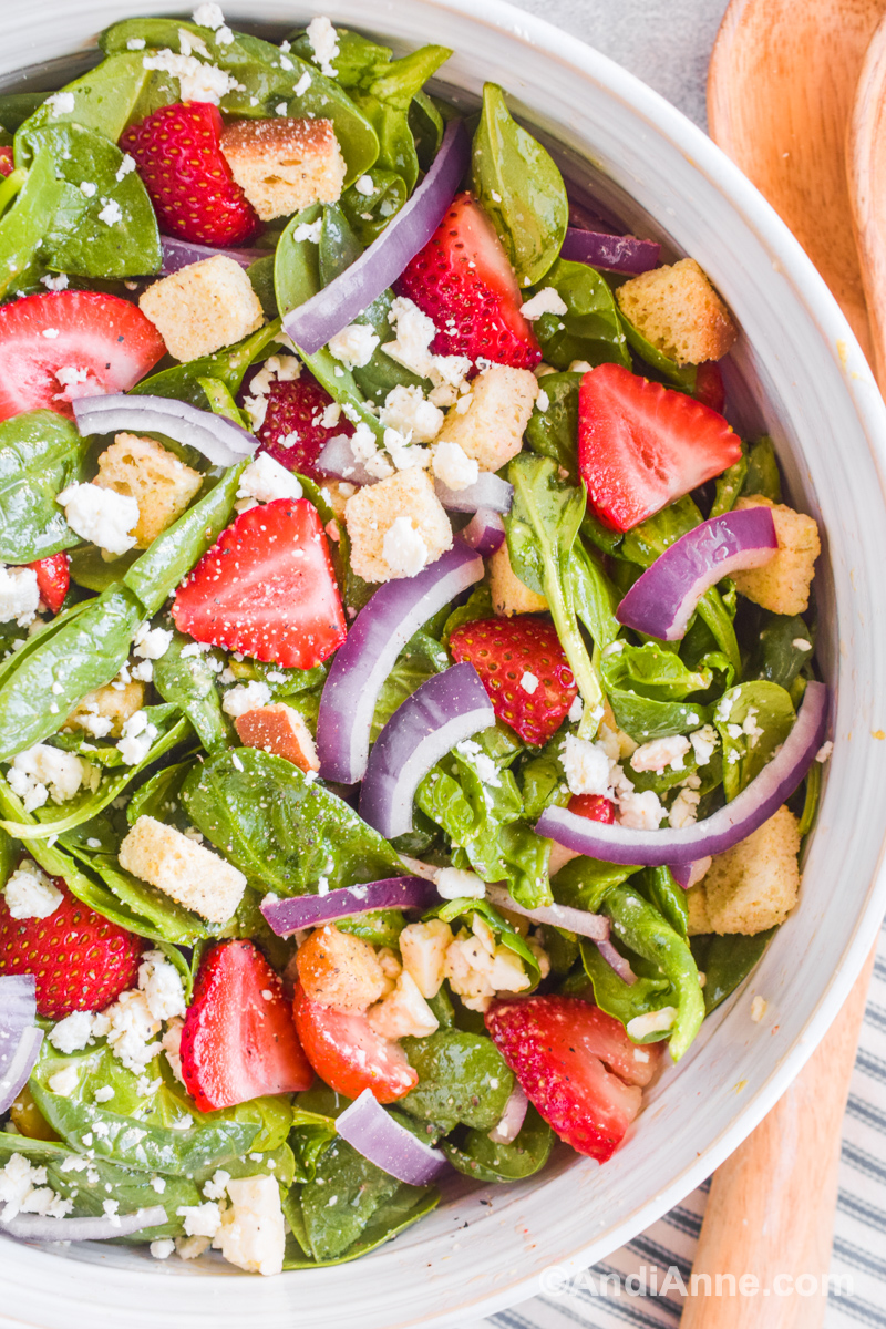 Close up detail of nut-free strawberry spinach salad in a white bowl. 