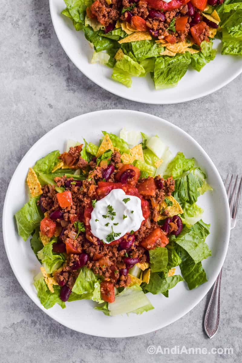 Looking down at plates of ground beef taco salad with forks beside.