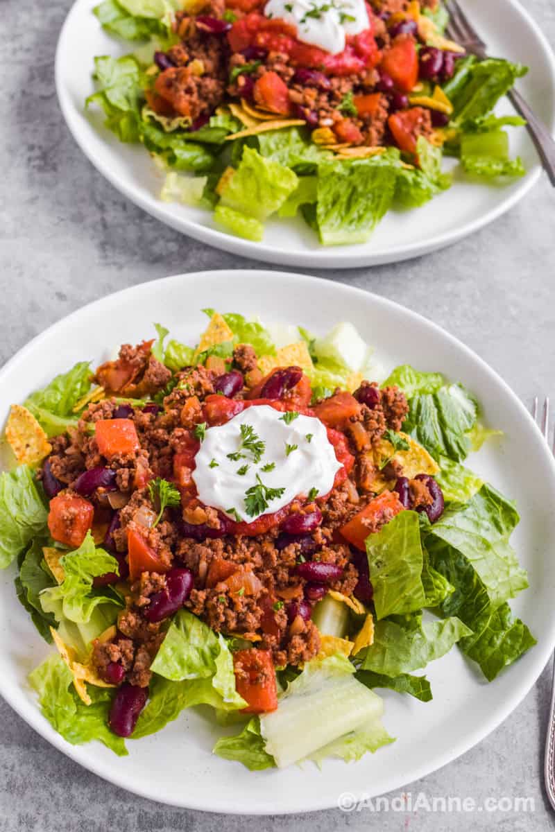 Close up side angle of salad with ground beef, lettuce, tortilla chips and sour cream.