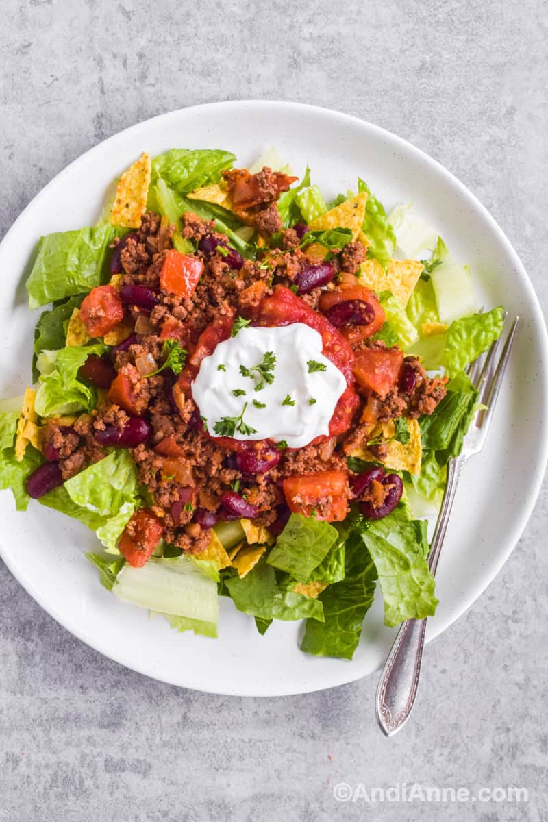 Looking down at taco ground beef salad with sour cream and fork.