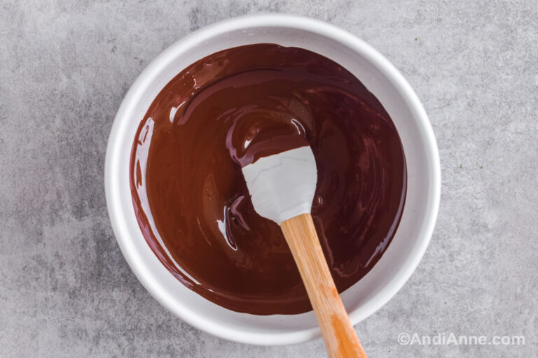 A white bowl with melted chocolate and a spatula.