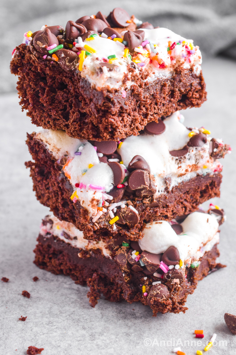 Three cake bars stacked on top of eachother, topped with melted marshmallows, chocolate chips and sprinkles.