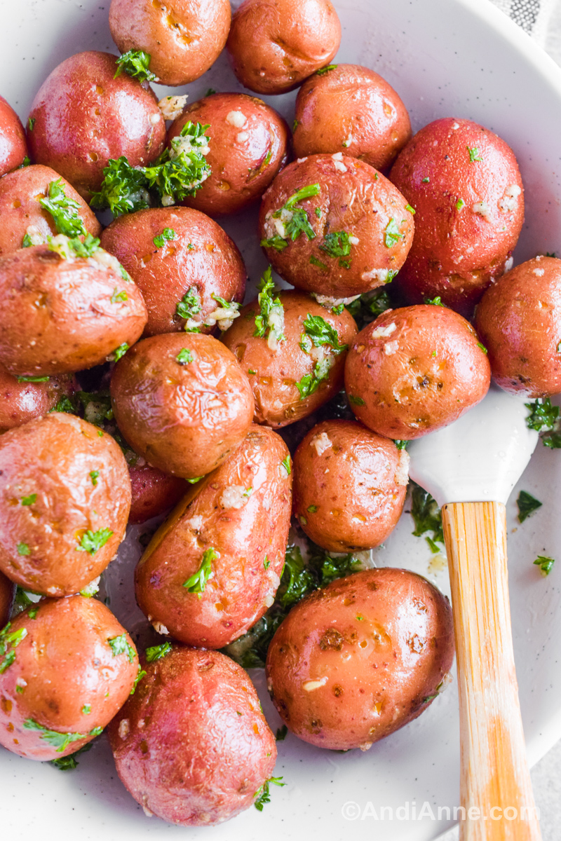 red baby potatoes with minced garlic and chopped parsley and spatula.
