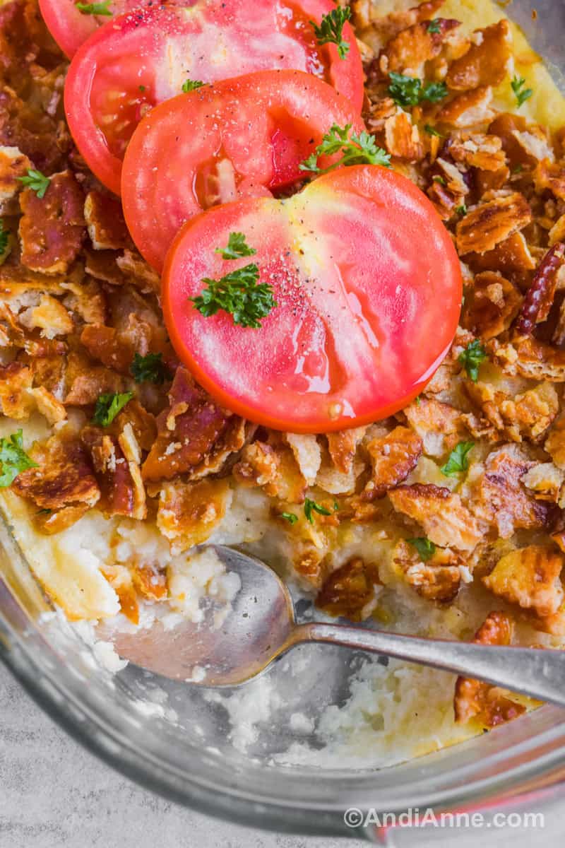 Close up of a spoon in turnip casserole with crushed crackers and tomato slices.