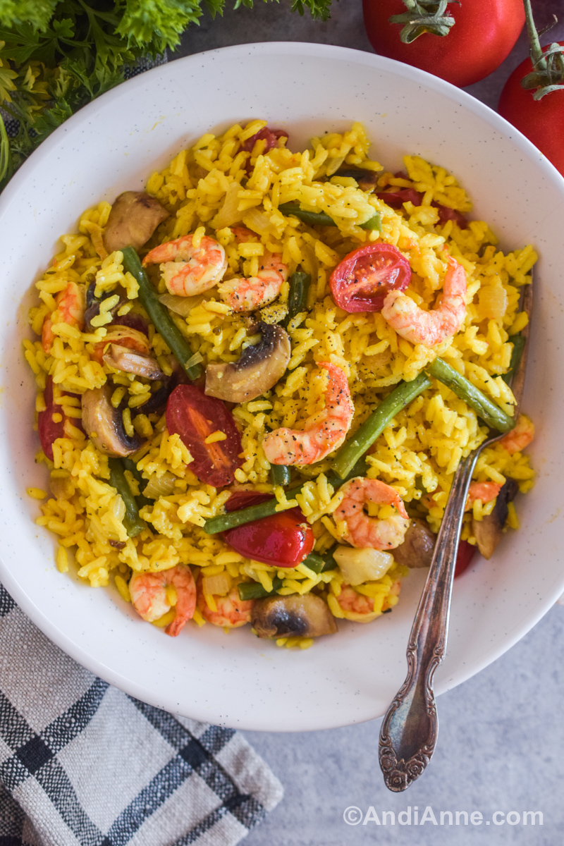Shrimp with turmeric rice recipe in a white bowl with a fork. 