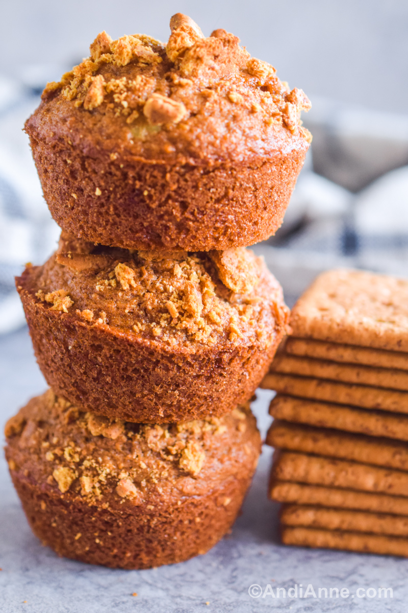 Three muffins stacked on top of each other with a pile of graham crackers beside them.