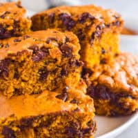 Pumpkin chocolate chip bars stacked on top of each other on a white plate.