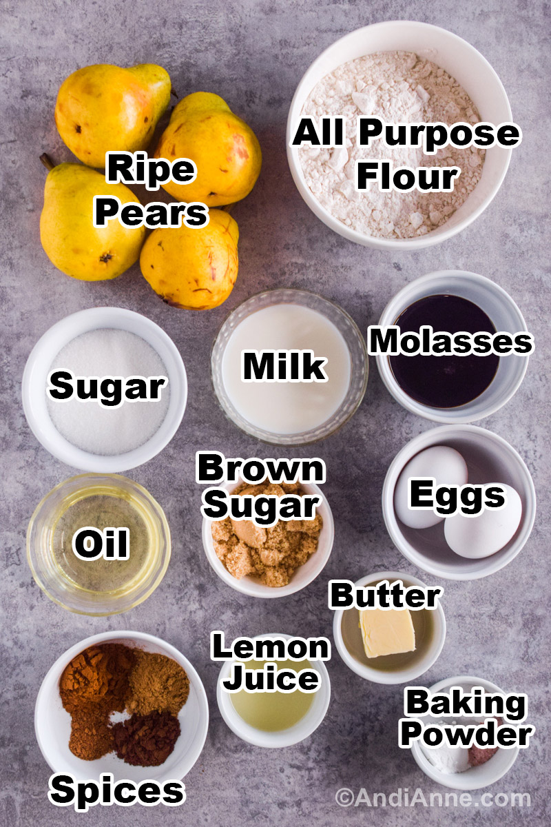 Recipe ingredients on the counter including ripe pears, and bowls of flour, sugar, milk, molasses, oil, brown sugar, eggs, spices, lemon juice, butter and baking powder.