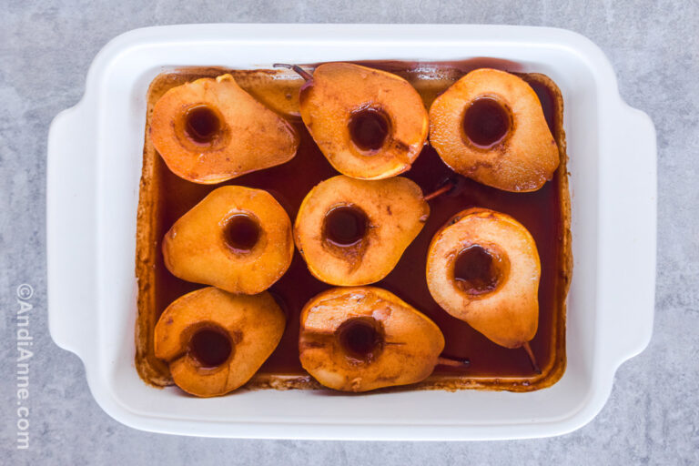Pears sliced in half in a casserole dish with brown sauce.
