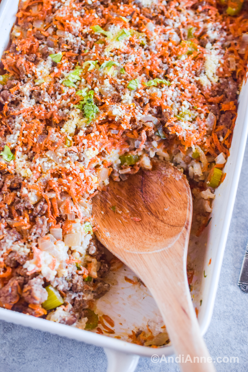 Close up of beef carrot rice casserole with a wooden spoon. 