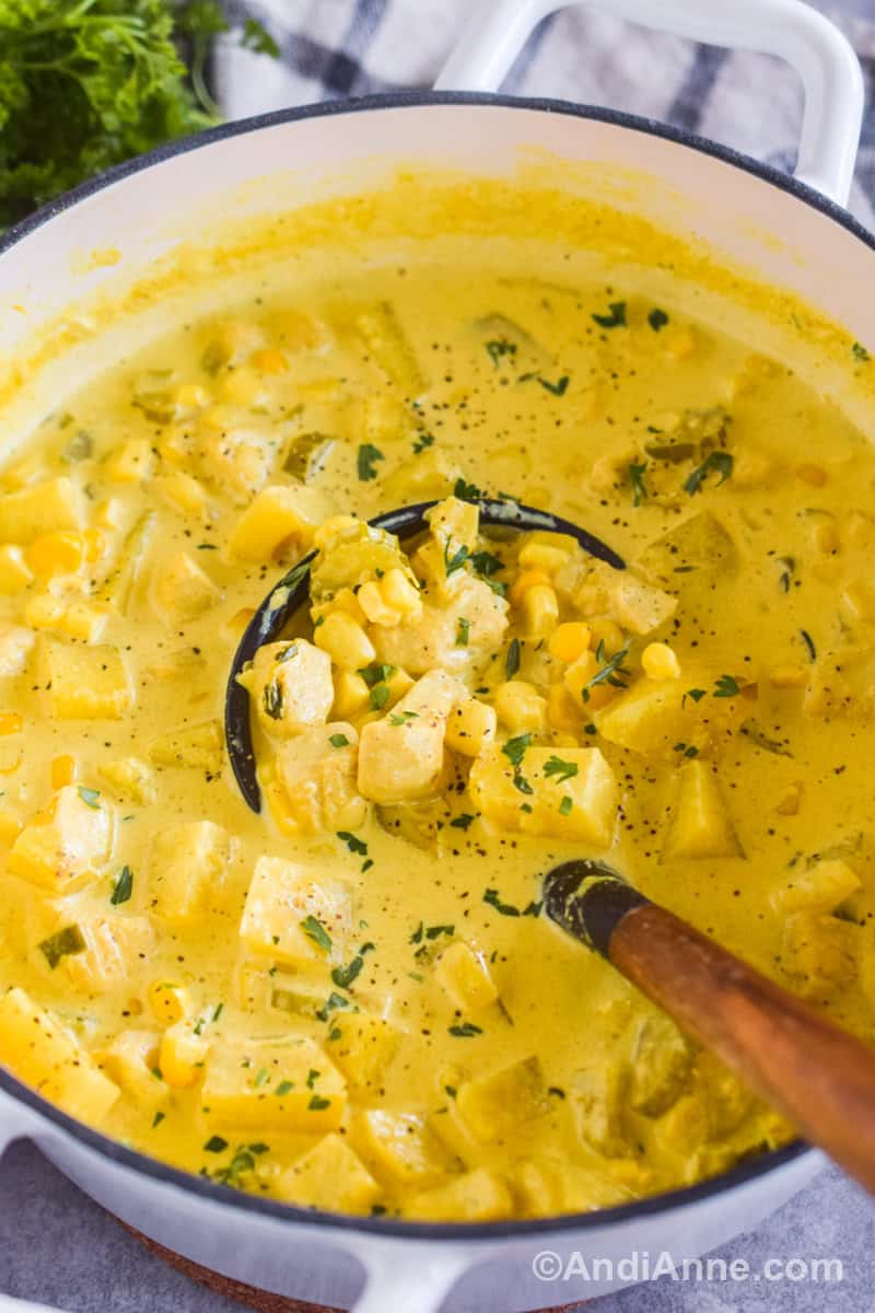 Close up of a pot with curry chicken corn chowder with a soup ladle.