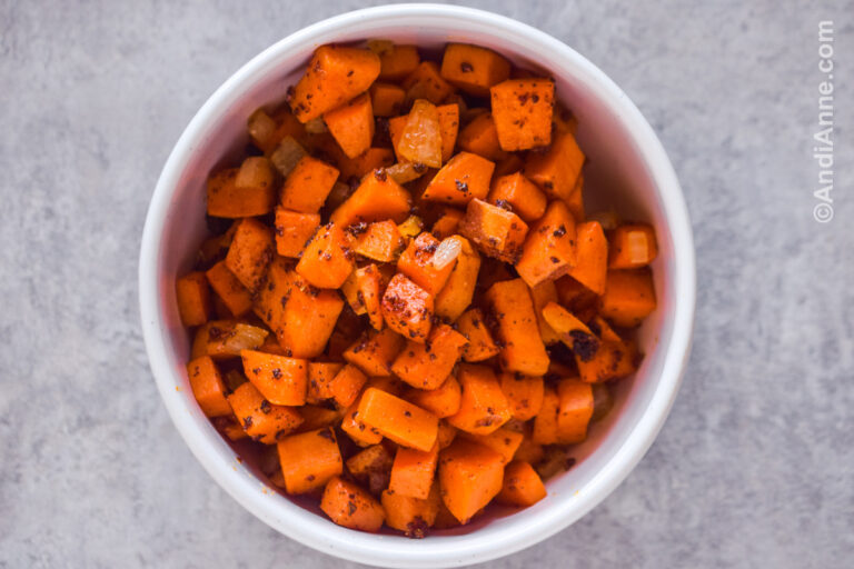 A white bowl of cooked chopped sweet potatoes.