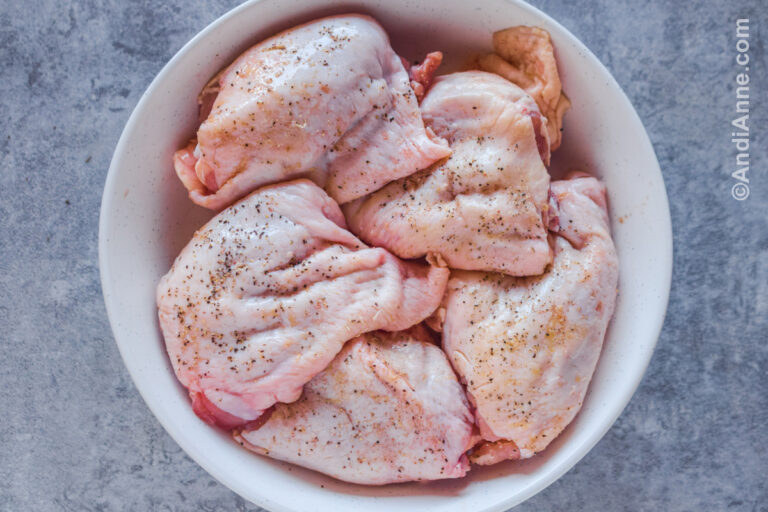 Raw chicken thighs in a white bowl.