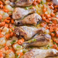Chicken legs and sweet potatoes on a baking sheet/