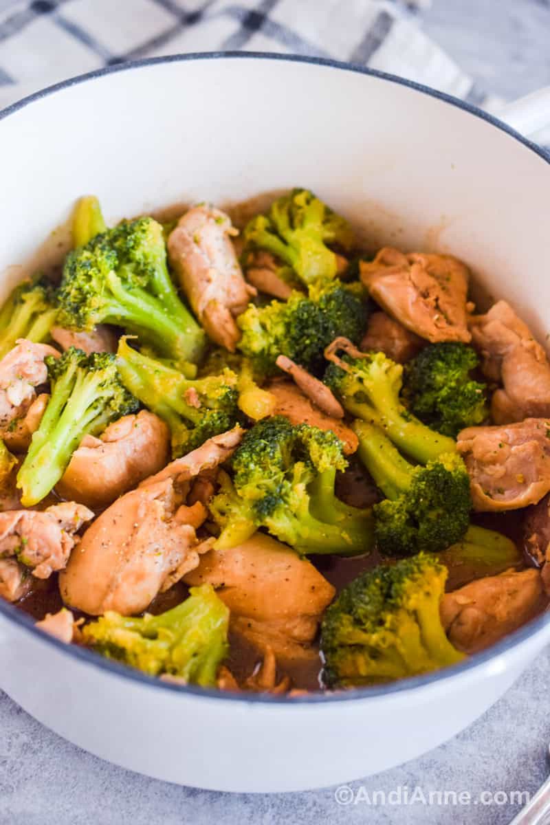 Cooked chicken thighs and broccoli in a white pot.