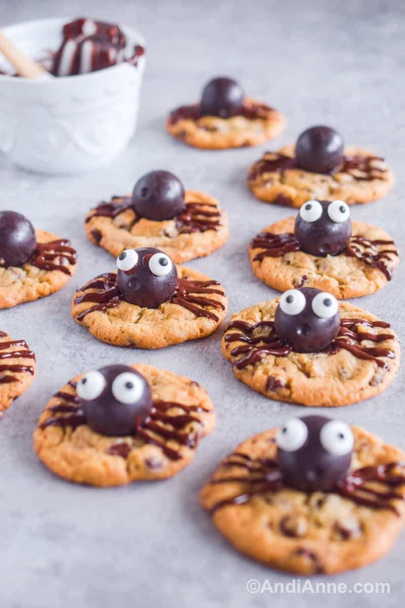 A bunch of cookies with chocolates and candies to look like spiders. All placed on a counter.